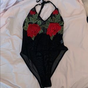 A see through black body suit with flowers.